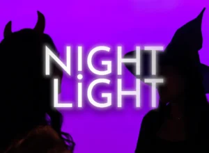 A silhouette image of two people wearing devils horns and a witch's hat. Text overlay reads Night Light.